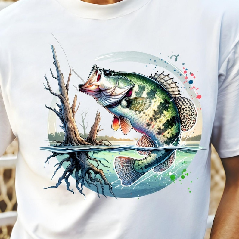 May include: A white t-shirt with a colorful illustration of a largemouth bass jumping out of the water. The fish is green, white, and black with red fins. The background is a blue and green watercolor design with a tree trunk and roots.