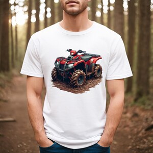 May include: White t-shirt featuring a red ATV graphic. The four-wheeler is depicted with large, rugged tires and is set against a muddy backdrop. The shirt is a classic crew neck style.