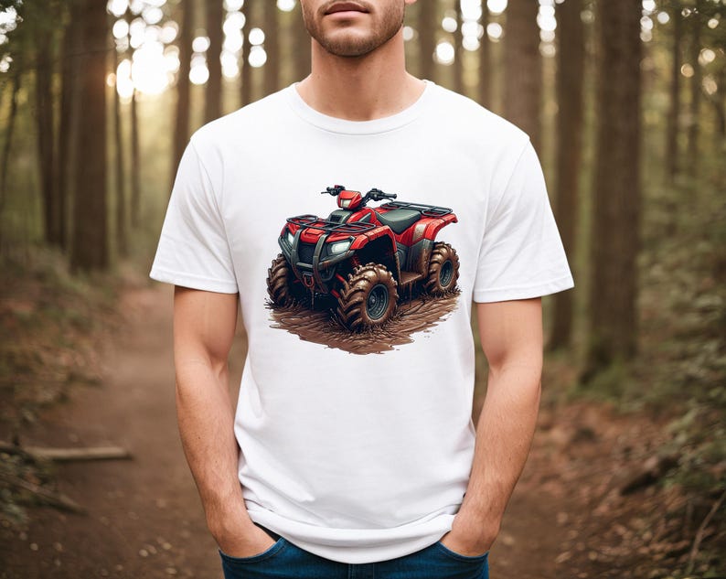 May include: White t-shirt featuring a red ATV graphic. The four-wheeler is depicted with large, rugged tires and is set against a muddy backdrop. The shirt is a classic crew neck style.
