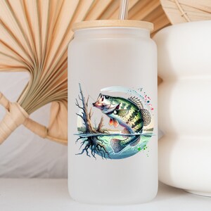 May include: A frosted glass water bottle with a bamboo lid and a straw. The bottle features a colorful illustration of a bass fish jumping out of the water.
