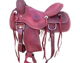 May include: A burgundy leather Western saddle with intricate tooling and stitching. The saddle features a high cantle, a horn, and stirrups. The brand name "TEXANTACK" is visible on the saddle. This equestrian equipment is designed for riding.