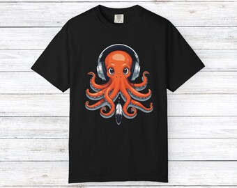 May include: Black t-shirt featuring a cartoon octopus wearing headphones. The octopus is orange with large eyes and tentacles. A feather is below the octopus. The shirt is made of a soft material.