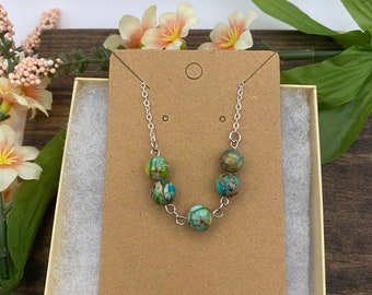 May include: A silver chain necklace with five green, blue and brown patterned beads.