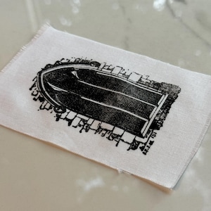 May include: A black and white printed fabric patch featuring a detailed illustration of an arched doorway with a brick pattern.