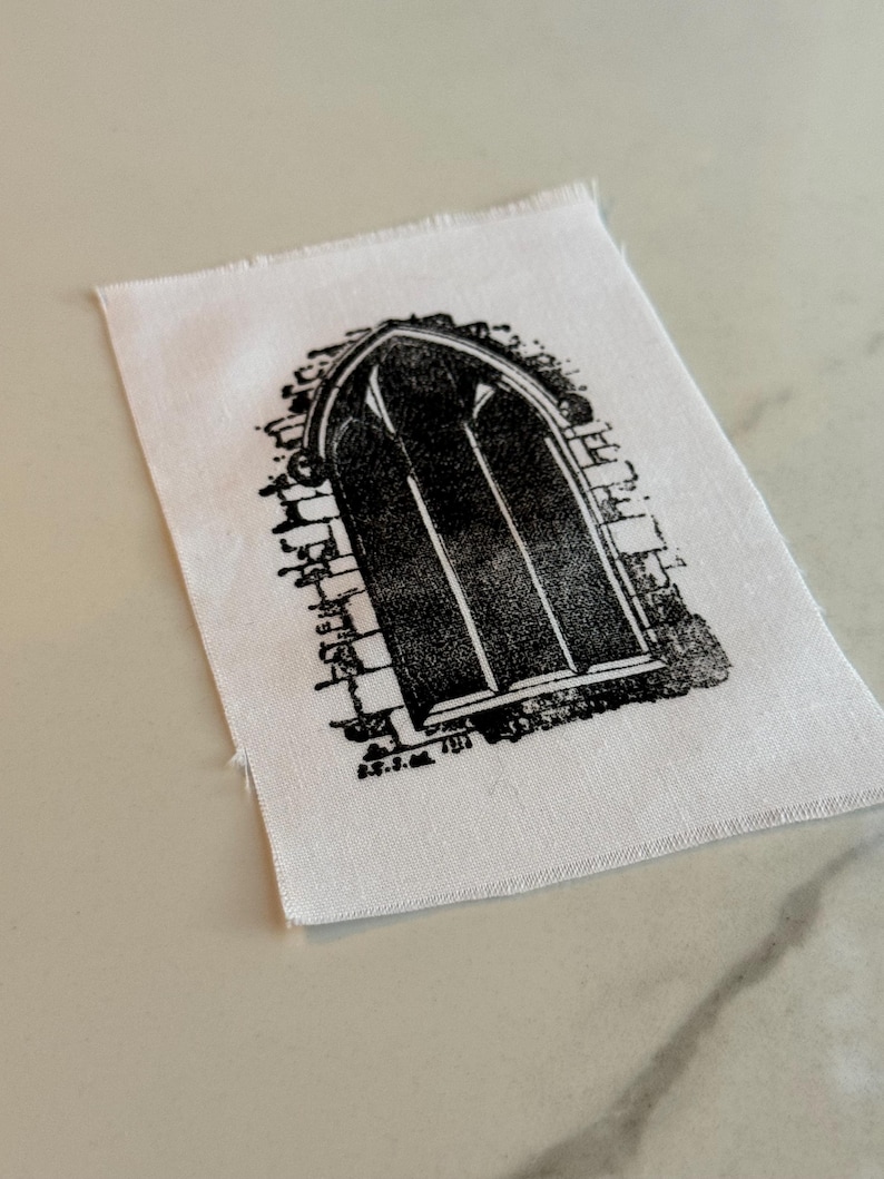 May include: Black and white iron-on patch featuring a detailed illustration of an arched window with a brick frame.