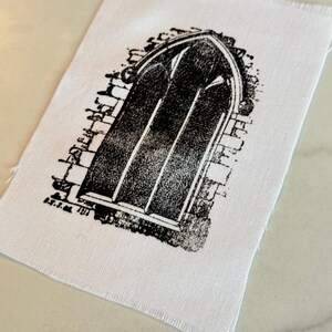 May include: Black and white printed patch of an arched window with brickwork around it.