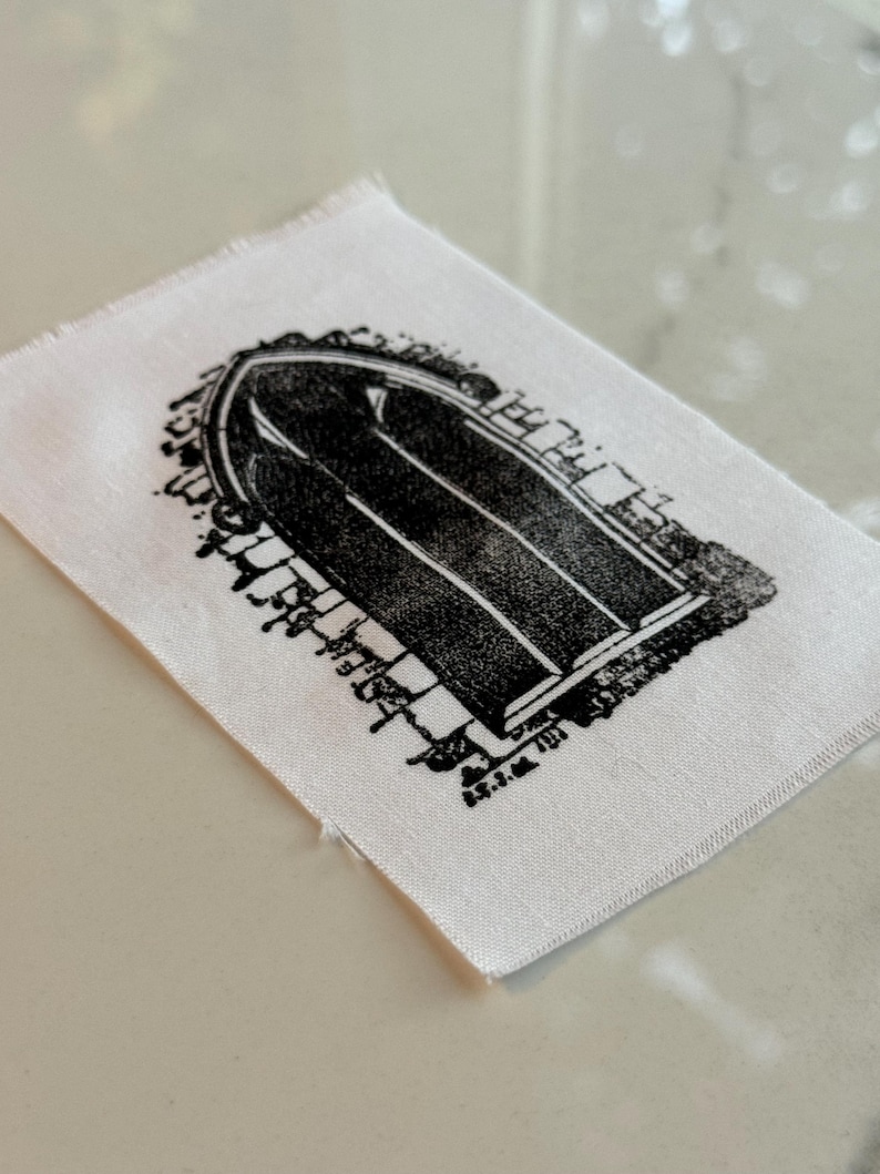 May include: A white fabric patch with a black and white print of an arched doorway.