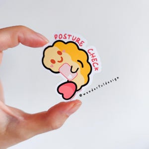 May include: A yellow and pink sticker featuring a cartoon character holding a phone. The character has a heart-shaped head and is smiling. The sticker reads "POSTURE CHECK" and "@wonderfuldesign".