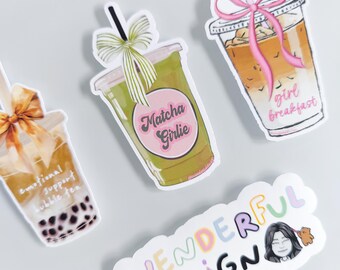 May include: Four die-cut stickers featuring three iced beverage cups with bows and text reading emotional support bubble tea, Matcha Girlie, and girl breakfast, plus a sticker with the text WENDERFUL DESIGN and a small illustrated face.