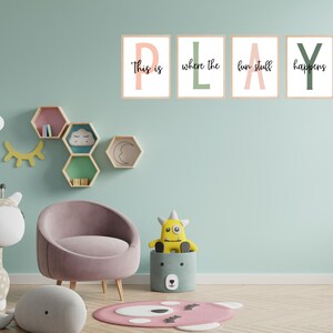 May include: A children's room scene with a light blue wall, featuring framed art spelling "PLAY". A pink armchair, stuffed giraffe, and other toys are present. Decorative shelves and a rug complete the playful decor.