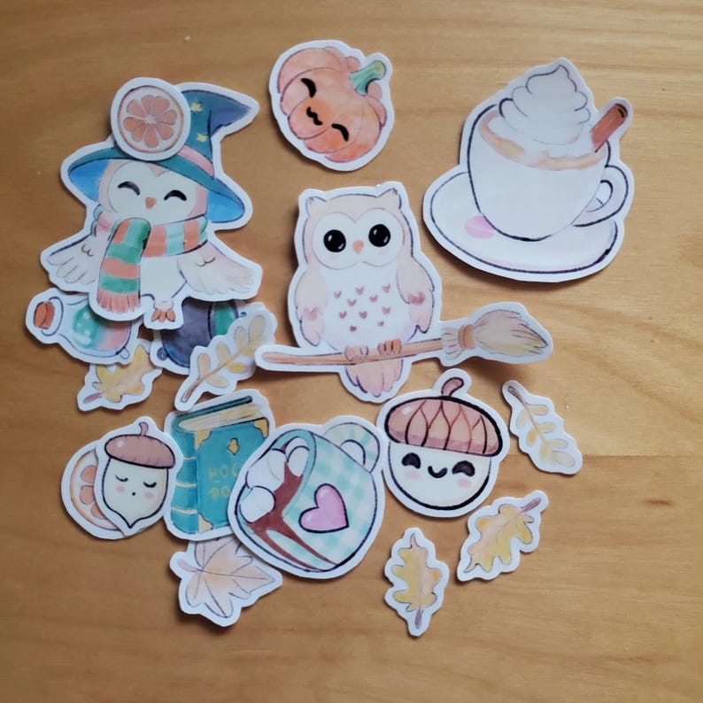 May include: A collection of fall-themed stickers featuring cartoon owls, pumpkins, acorns, leaves, and a coffee cup. The stickers have a whimsical design with soft colors, including orange, blue, and brown. Some stickers have a witchy theme.