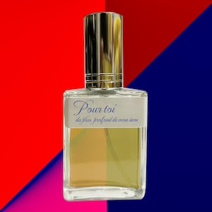 May include: A rectangular perfume bottle with a silver cap and a clear glass body. The bottle has a label with the words "Pour toi" and "du plus profond de mon âme" in blue script. The background is divided diagonally into red and blue sections.