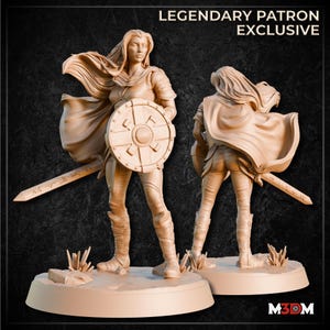May include: A beige figurine of a female warrior holding a shield and sword, with a cape. The figurine is standing on a base with the text "LEGENDARY PATRON EXCLUSIVE" at the top. The figurine is shown from the front and back.