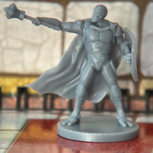 May include: A gray miniature figurine of a knight in armor, holding a mace and shield. The knight has a flowing cape and is standing on a circular base. The figurine is likely for a tabletop game.