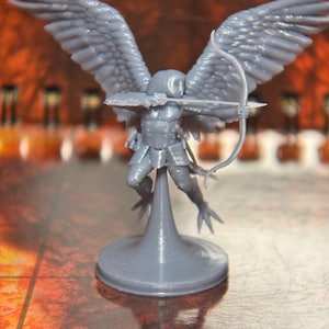 May include: A gray 3D printed miniature of an angel with wings outstretched, holding a bow and arrow. The angel is standing on a round base.