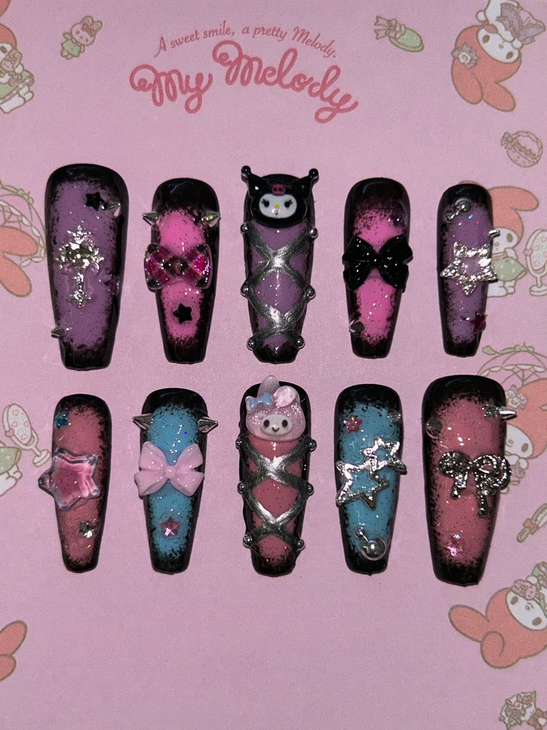 May include: A set of ten long, coffin-shaped press-on nails. Each nail features a unique design with a black and pink ombre effect, adorned with bows, stars, and character embellishments. The background reads "A sweet smile, a pretty Melody, My Melody."