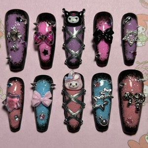 May include: A set of ten long, coffin-shaped press-on nails. Each nail features a gradient design with black tips and various embellishments, including bows, stars, and character designs. The nails are decorated with glitter and silver accents.