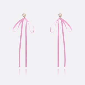 May include: A pair of pink ribbon earrings with a pearl and gold accent.