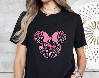 Könnte beinhalten: Schwarzes T-Shirt mit einem rosafarbenen Mickey-Maus-Silhouetten-Design mit rosafarbenen Bändern und anderen kleinen rosafarbenen Designs.