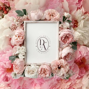 Op de afbeelding: Een witte rechthoekige fotolijst met een verweerde afwerking, omringd door een arrangement van roze en witte pioenrozen en rozen. Het midden van de lijst toont een logo met de tekst "DIGITAL ARTISTRI CREATIONS".