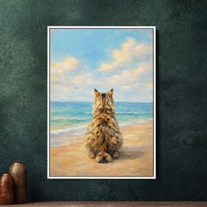 Może przedstawiać: Oprawiony obraz przedstawiający kota od tyłu, patrzącego na morze. Kot ma brązowe i beżowe futro, siedzi na piaszczystej plaży. Niebo jest niebieskie z białymi chmurami, a ocean to mieszanka błękitu i turkusu.