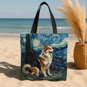 Op de afbeelding: Tote bag met een hond in de stijl van Van Goghs "Starry Night". De hond heeft bruin, wit en zwart haar, tegen een wervelende blauwe en gele nachthemel. De tas heeft zwarte handvatten en staat op een zandstrand.