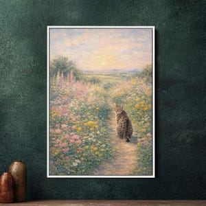 Op de afbeelding: Een ingelijst schilderij toont een tabby kat op een pad door een veld met wilde bloemen. Het kunstwerk gebruikt een zacht palet van roze, geel en groen, met een zonsondergang op de achtergrond. Het schilderij wordt gepresenteerd in een witte lijst.