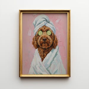 May include: A framed painting of a brown dog wearing a white towel on its head and a white robe. The dog has cucumber slices over its eyes, set against a pink background. The frame is gold.