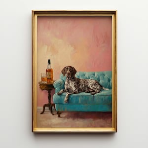May include: A framed painting depicts a brown and white dog lying on a teal blue sofa. A small table holds a bottle of liquor and a glass. The background is a blend of pink and peach hues, and the frame is gold.