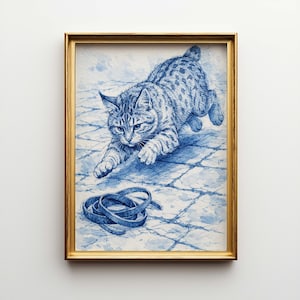 May include: A framed blue and white illustration of a cat pouncing towards a coiled blue leash. The cat has a spotted coat and is set against a tiled background. The frame is gold.