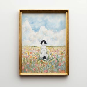 May include: A framed watercolour painting shows a black and white dog seated in a field of colourful flowers, viewed from behind. The sky is blue with fluffy white clouds. The frame is gold.