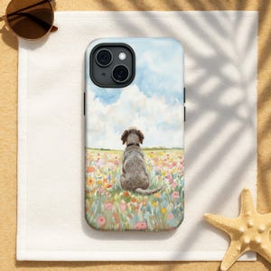 May include: A phone case featuring a watercolor painting of a dog sitting in a field of colorful flowers under a blue sky with fluffy clouds. The case is on a white towel with sunglasses and a starfish.