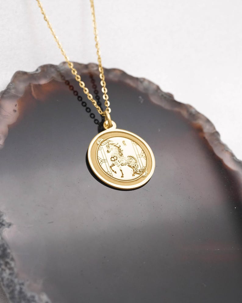 Macro close-up of the 14k solid gold Year of the Horse medallion pendant, focusing on the engraved horse artwork and bright reflective polish. Inspired by Chinese zodiac symbolism of vitality, confidence, and forward progress, this coin necklace suits minimal style and daily wear. SEO: Chinese zodiac pendant, horse necklace, astrology necklace, lunar new year gift, gold charm necklace, handcrafted fine jewelry with crisp detailing.