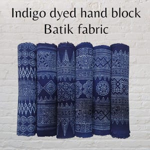 May include: Indigo dyed hand block batik fabric in a variety of patterns. The fabric is rolled up and the patterns are visible on the surface.