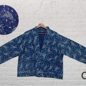 May include: A blue and white patterned kimono-style jacket with a traditional Japanese design. The jacket has a relaxed fit and a V-neckline. The fabric is soft and comfortable.