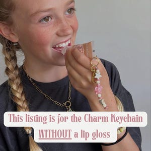 May include: A charm keychain with a gold-colored ring, featuring pink, white, and green beads, a star, and a turtle charm. The text on the image reads: "This listing is for the Charm Keychain WITHOUT a lip gloss."