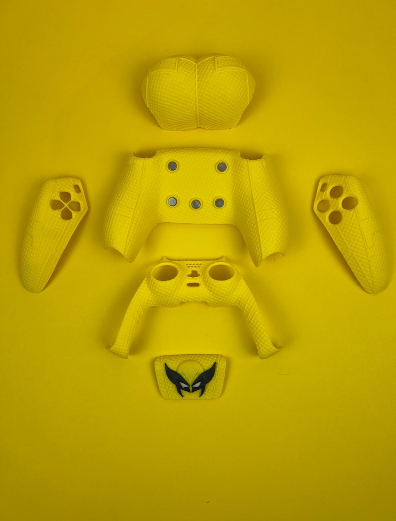 May include: A yellow Xbox controller skin with a Wolverine character design. The skin is made up of separate pieces for the front, back, and sides of the controller.