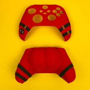 May include: Red and black Xbox controller skin with a Deadpool design. The skin is made of silicone and has a textured surface. The skin is designed to fit the Xbox Series X controller.