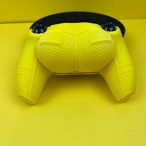 May include: A bright yellow textured silicone controller cover for a gaming console.