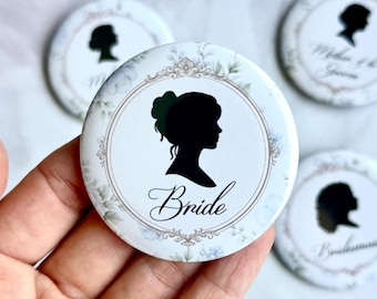 May include: A collection of white round buttons with a floral design and a black silhouette of a woman's profile. The word "Bride" is written in elegant script below the silhouette. Other buttons feature silhouettes and text.