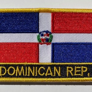 May include: Embroidered patch with the Dominican Republic flag. The flag is red, white, and blue with a coat of arms in the center. The patch has a gold border and the words "DOMINICAN REP." in black letters.