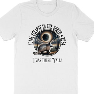 May include: White t-shirt with a black circle graphic featuring a total eclipse in the south 2024 with an armadillo in the foreground. The text "I was there Y'all!" is below the circle.