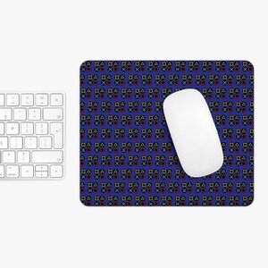 May include: A rectangular mousepad with a blue background features a repeating pattern of colorful game controller symbols. A white wireless mouse rests on the pad, next to a white keyboard.