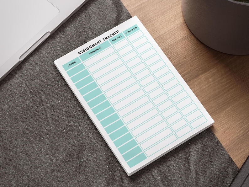 以下が含まれることがあります： 水色のグリッドデザインの白い宿題トラッカーメモ帳。「Assignment Tracker」とラベル付けされ、コース、課題、期日、完了ステータスのセクションが含まれています。 灰色の表面にメモ帳があります。