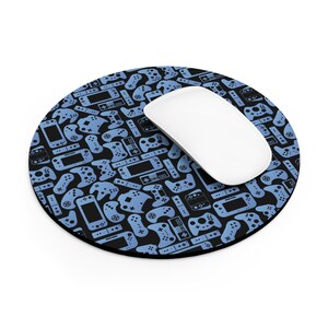 May include: A round black mousepad with a blue video game controller pattern. A white computer mouse rests on the pad. The pattern includes various game console designs.
