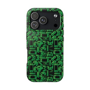 Puede incluir: Funda de teléfono verde y negra con un patrón repetido de mandos y consolas de videojuegos. La funda tiene un acabado brillante y está diseñada para un smartphone, con recortes para las lentes de la cámara.