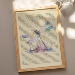 Könnte beinhalten: Ein Aquarellbild einer Libelle mit schillernden Flügeln vor dem Hintergrund einer alten Buchseite mit Text. Die Libelle ist in Blautönen, Grün- und Violetttönen mit einem Hauch von Gold gemalt. Die Buchseite ist verblasst und hat einen Vintage-Charakter.