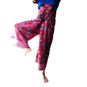 Puede incluir: Pantalones de pierna ancha con un patrón rojo y azul. Los pantalones están atados a la cintura con un nudo.