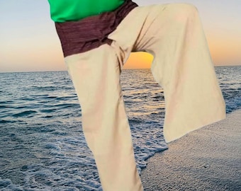 May include: Wide-leg trousers in a light beige color featuring a dark brown wrap-around waistband. The trousers are paired with a bright green short-sleeved top. The garment has a loose, flowing fit with a distinct wrap-style waist detail.