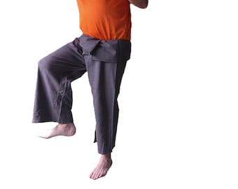 May include: An orange t-shirt paired with dark gray wrap-style trousers. The trousers feature a wide-leg cut with a folded waistband design that overlaps at the front, creating a distinct layered appearance around the waist and hips.
